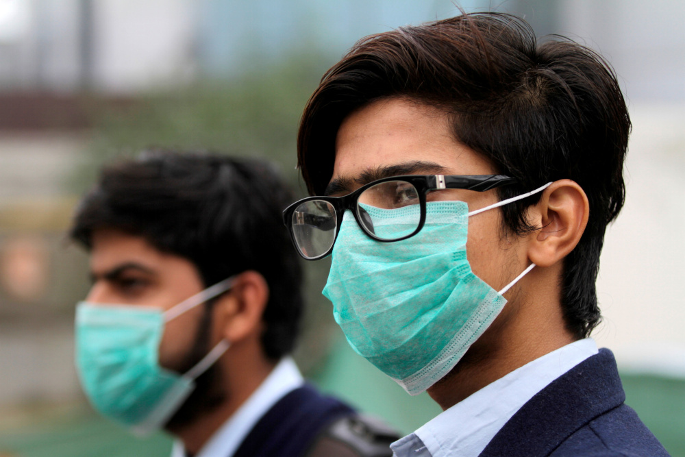 Men wearing protective masks wait for a bus in Lahore, Pakistan November 22, 2019. u00e2u20acu201d Reuters pic