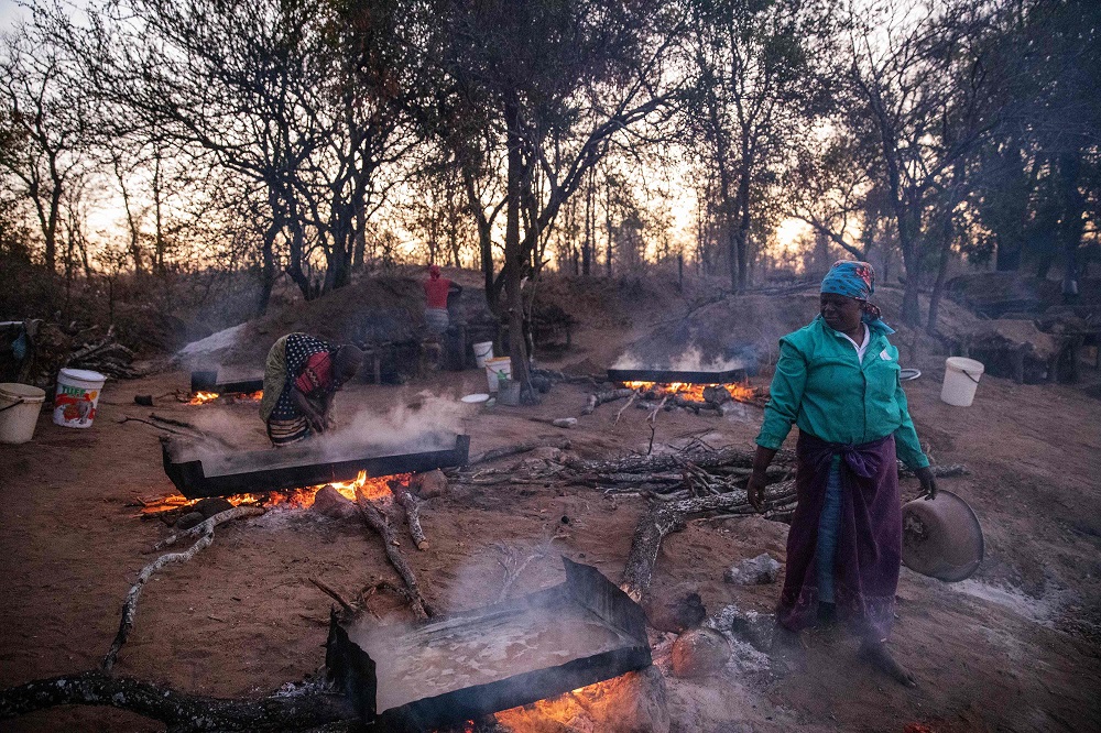 Josephine Macete, 48, (right) oversees salt-rich water boiling on the bank of the Klein Letaba River near Baleni, in the South African province of Limpopo, on August 26, 2019. — AFP pic