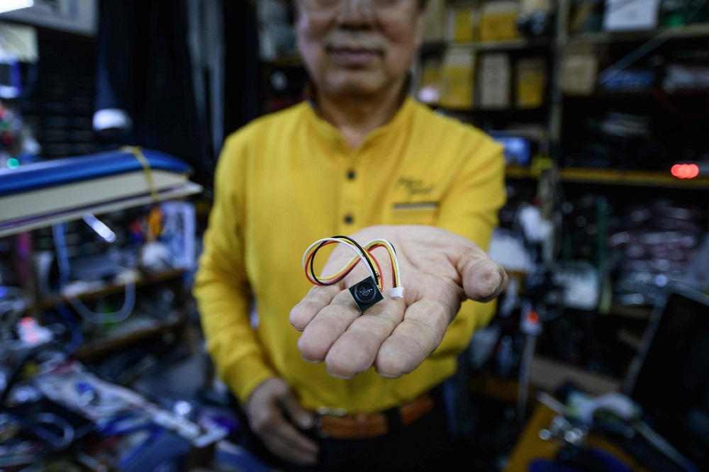 In a photo taken on March 26, 2019, electrical component vendor and technician Lee Seung-yon holds a mini camera unit capable of being built into custom-made devices, at his store in a market in Seoul. — AFP pic
