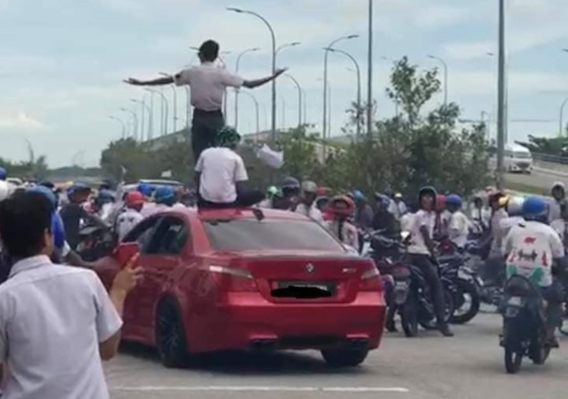 A student stands on top of a red BMW, as the group brought traffic to a standstill at Klebang, Melaka yesterday. u00e2u20acu201d Picture from Facebook/ We Are Malaysians