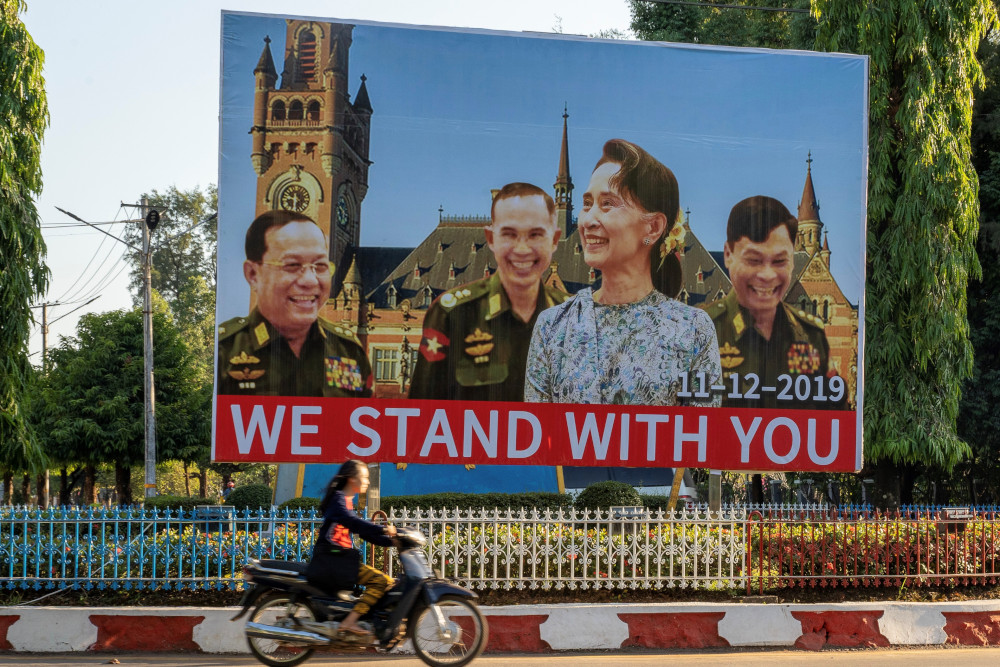 In this photo taken November 28, 2019, a woman on a motorcycle rides past a huge billboard depicting Myanmar State Counsellor Aung San Su Kyi with the three military ministers along a main road in Hpa-an, Karen State. u00e2u20acu201d AFP pic 