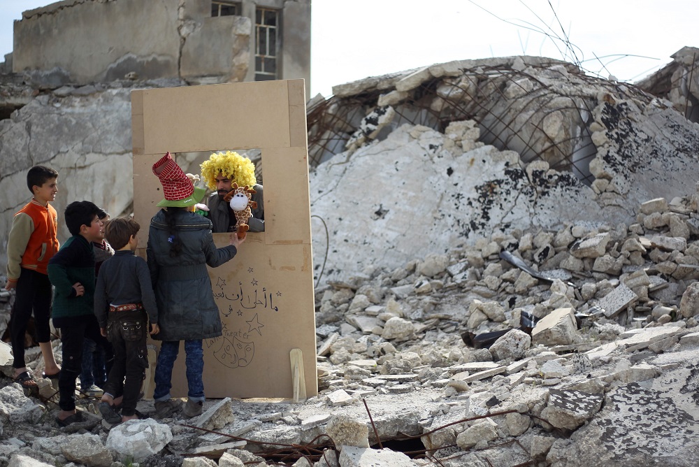 Syrian actor Walid Abu Rashed interacts with children through his makeshift puppet theatre set up among the rubble of collapsed buildings in the town of Saraqib in the rebel-held northern Idlib province March 27, 2019. — AFP pic