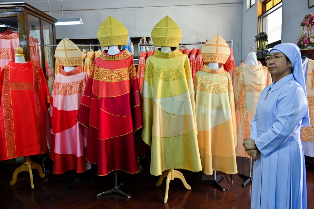 The two finished silk robes of Pope Francis (3rd, 4th left) are displayed along with robes of cardinals and bishops as Thai Sister Sukanya (right) looks on at the Praharuthai Convent in Bangkok November 11, 2019. u00e2u20acu201d AFP