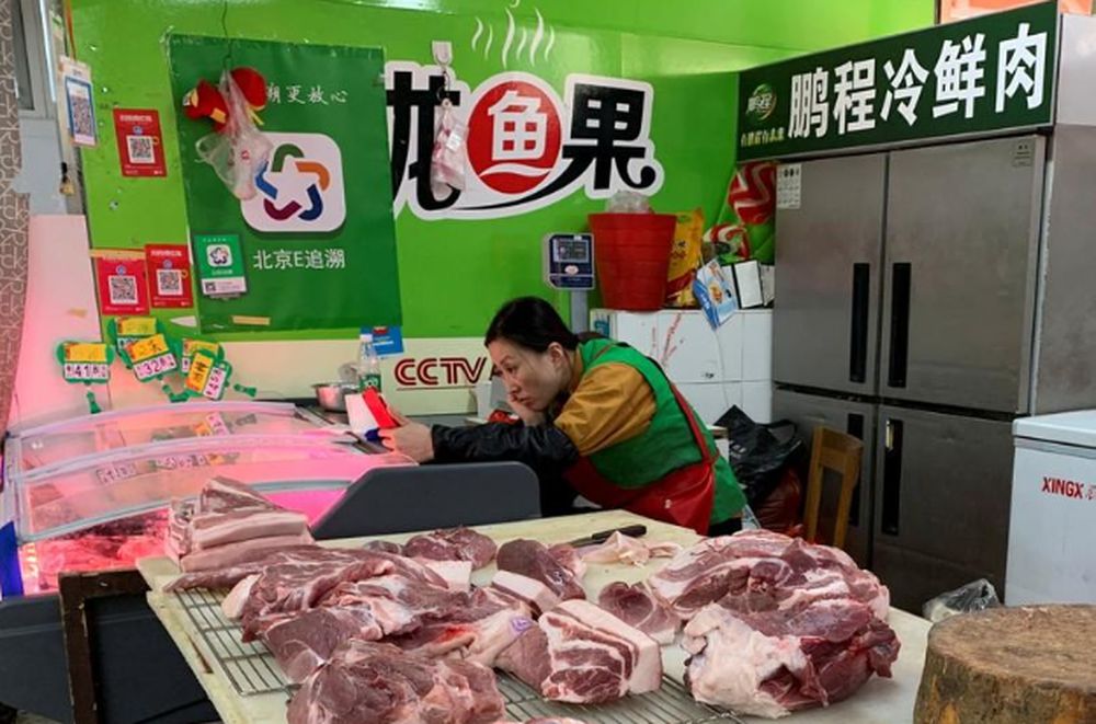 A pork vendor checks her smartphone while waiting for customers at a market in Beijing, China, November 11, 2019. u00e2u20acu201d Reuters pic