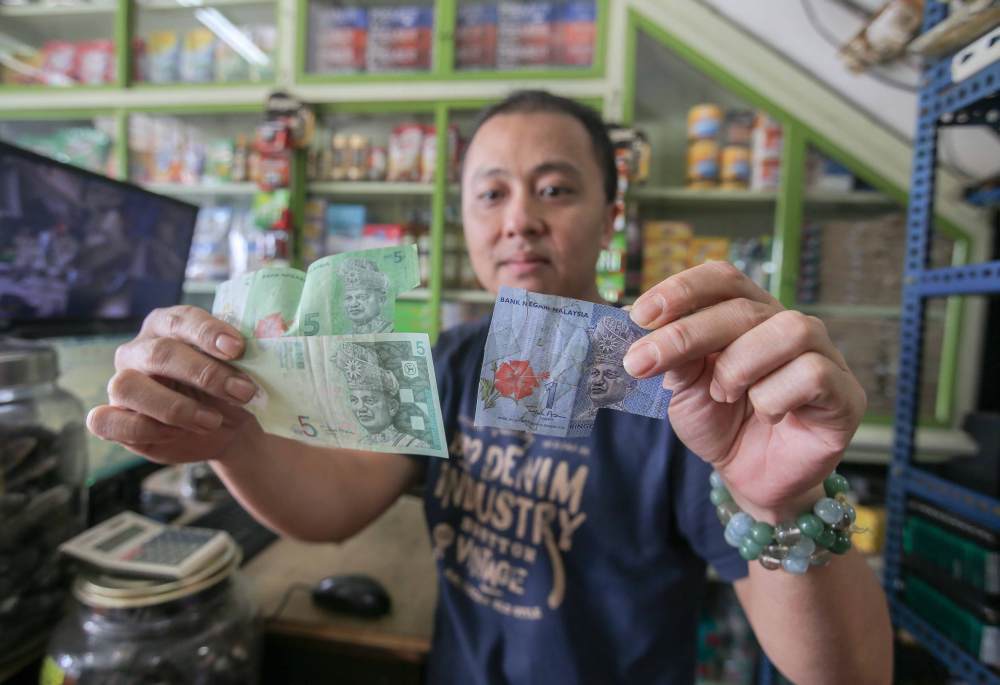 Sharikat Choy’s owner Choy Chi Choong shows the damaged notes he received from customers.