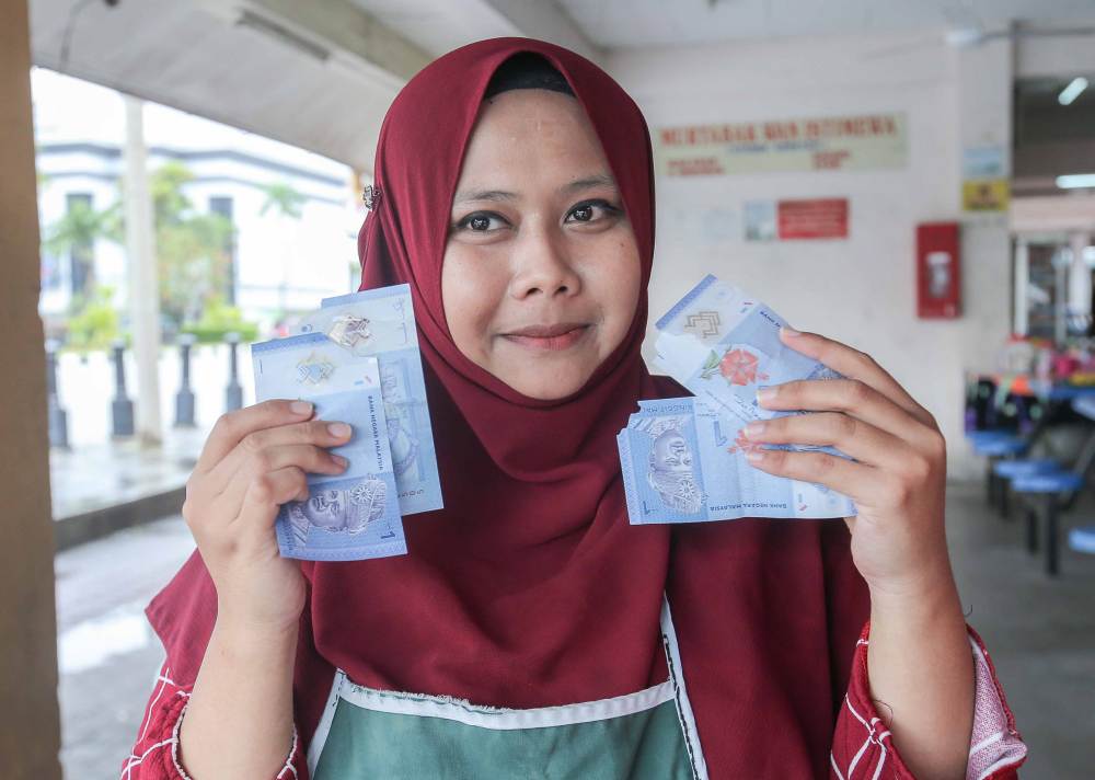 Trader Noor Syazlidn Mohd Yusof shows the torn notes she received from customers.
