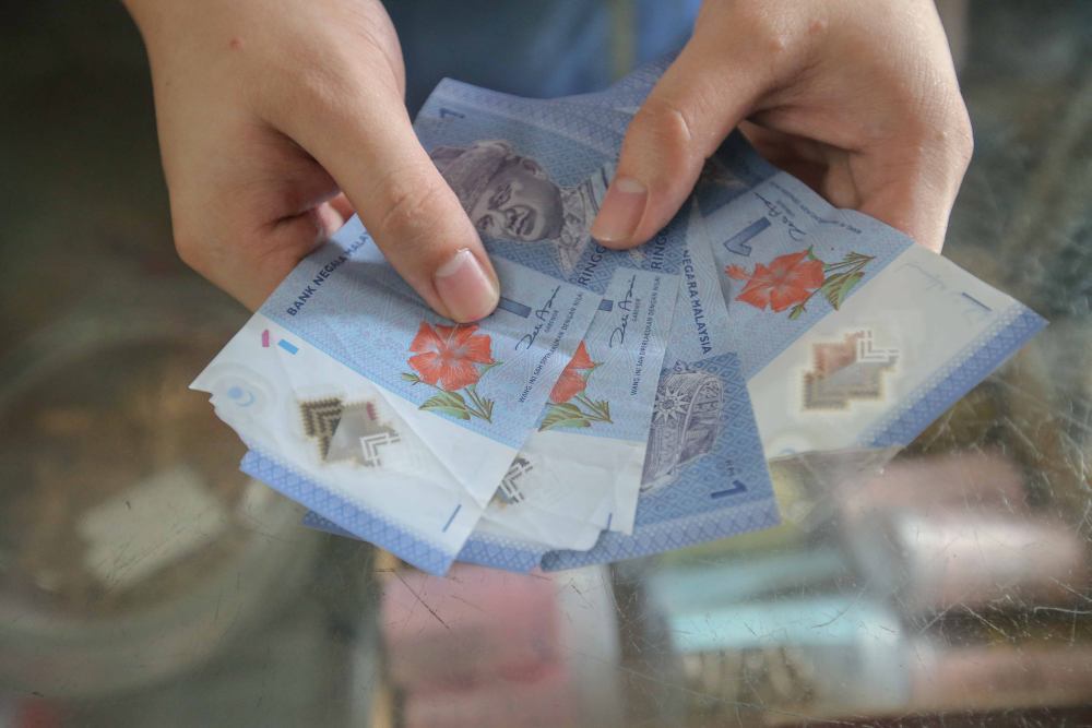 A trader shows the torn notes she received from customers. u00e2u20acu2022 Picture by Farhan Najib