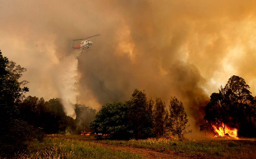 A fire bombing helicopter works to contain a bushfire along Old Bar road in Old Bar, New South Wales, Australia November 9, 2019. u00e2u20acu201d AAP Image/Shane Chalker via Reuters