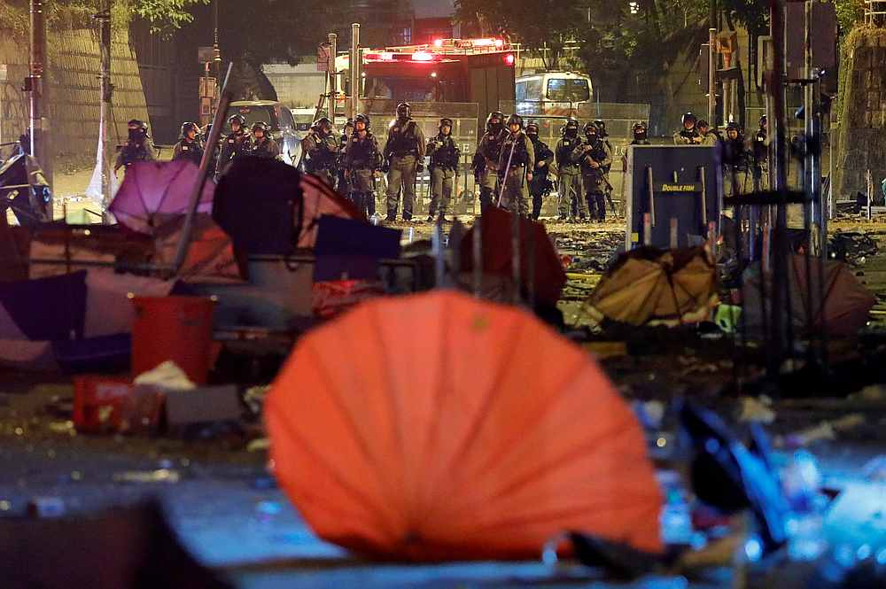 Police officers stand guard in front of a street scattered with umbrellas outside Hong Kong Polytechnic University (PolyU) in Hong Kong November 19, 2019. u00e2u20acu201d Reuters pic