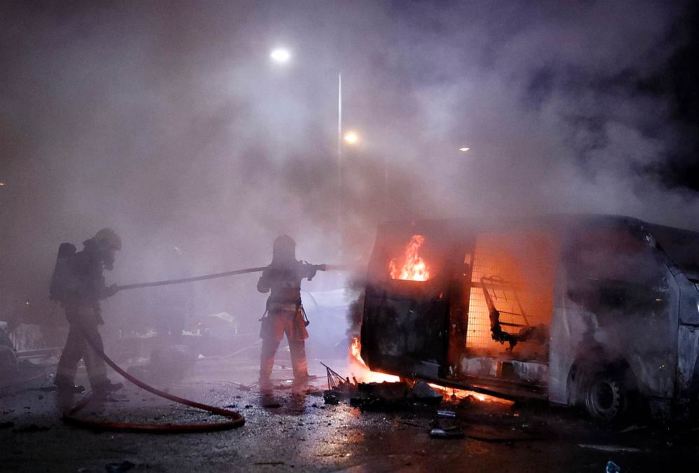 Firefighters extinguish a fire from explosions in an abandoned car, set up by protesters, near a barricade above the Tolo Highway next to the Chinese University campus in Hong Kong November 15, 2019. — Reuters pic