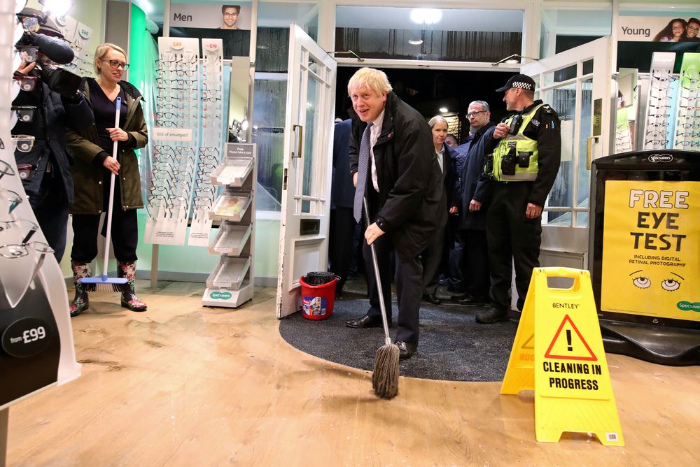 Britainu00e2u20acu2122s Prime Minister Boris Johnson mops the floor to help with the clean-up at an opticians during a visit to the flood-hit town of Matlock, Derbyshire, Britain November 8, 2019. u00e2u20acu201d Danny Lawson/Pool pic via Reuters