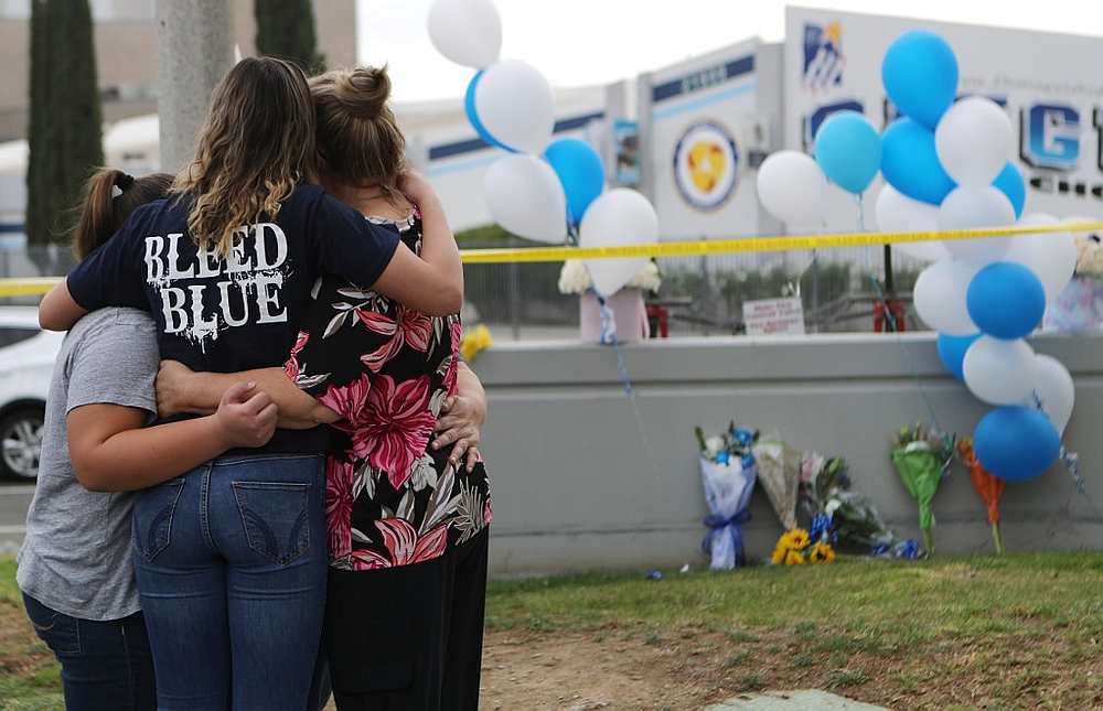 A Saugus High School student (second left) is embraced as she visits a makeshift memorial in front of the school for victims of the shooting in Santa Clarita, California November 15, 2019. u00e2u20acu201d AFP pic