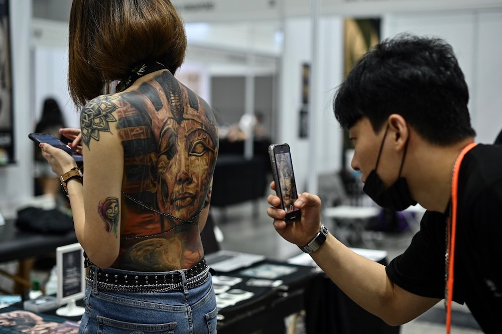 A man takes pictures of a woman with tattoos during the Tattoo Malaysia Expo 2019 in Kuala Lumpur November 29, 2019. u00e2u20acu201d AFP pic