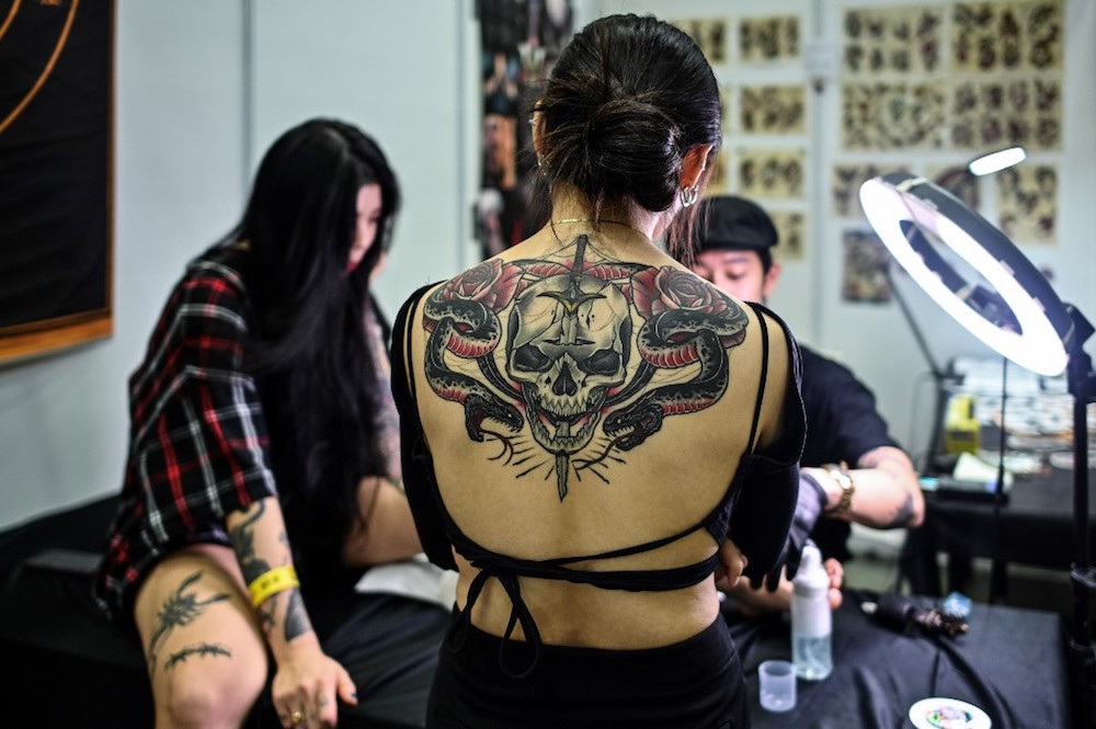 A woman with tattoos watches an artist work during the Tattoo Malaysia Expo 2019 in Kuala Lumpur November 29, 2019. — AFP pic