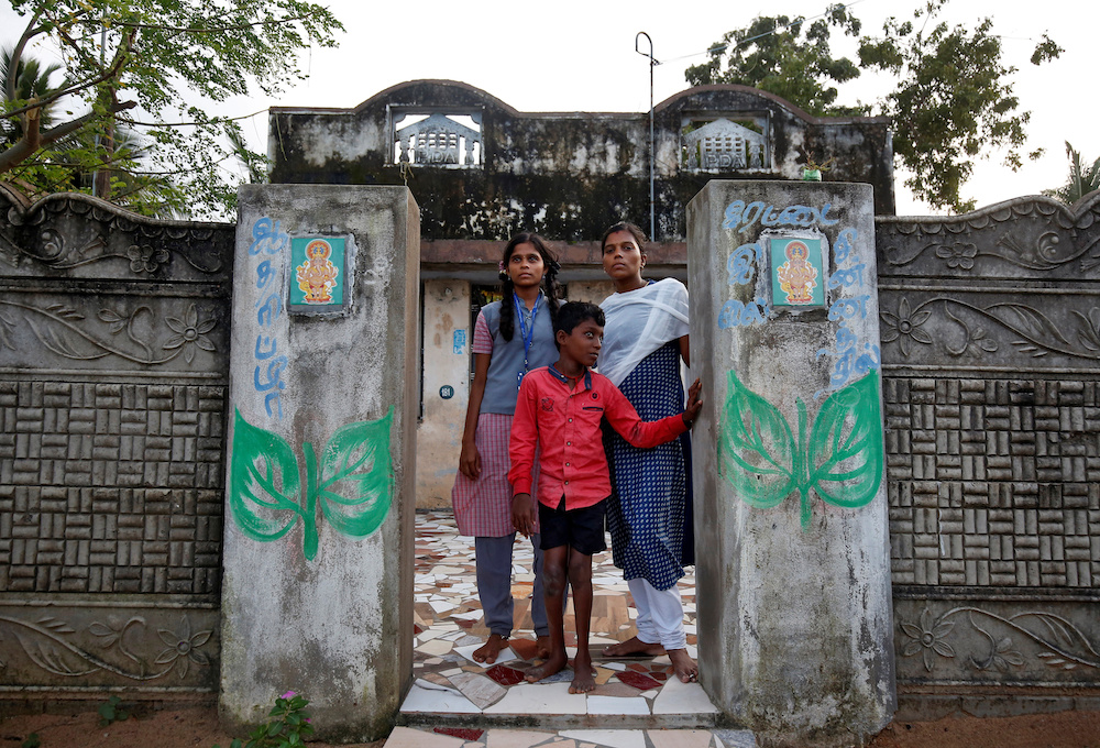 Saranya (right), who lost four siblings and her family home in the tsunami that killed more than 230,000 people, poses with her younger sister Reena and their brother Mohan outside a house in Nagapattinam district in Tamil Nadu December 4, 2019. u00e2u20acu201d Reute