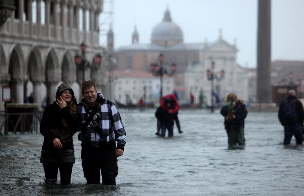 People walk through a flooded street during a period of seasonal high water in Venice November 11, 2012. u00e2u20acu201d Reuters pic