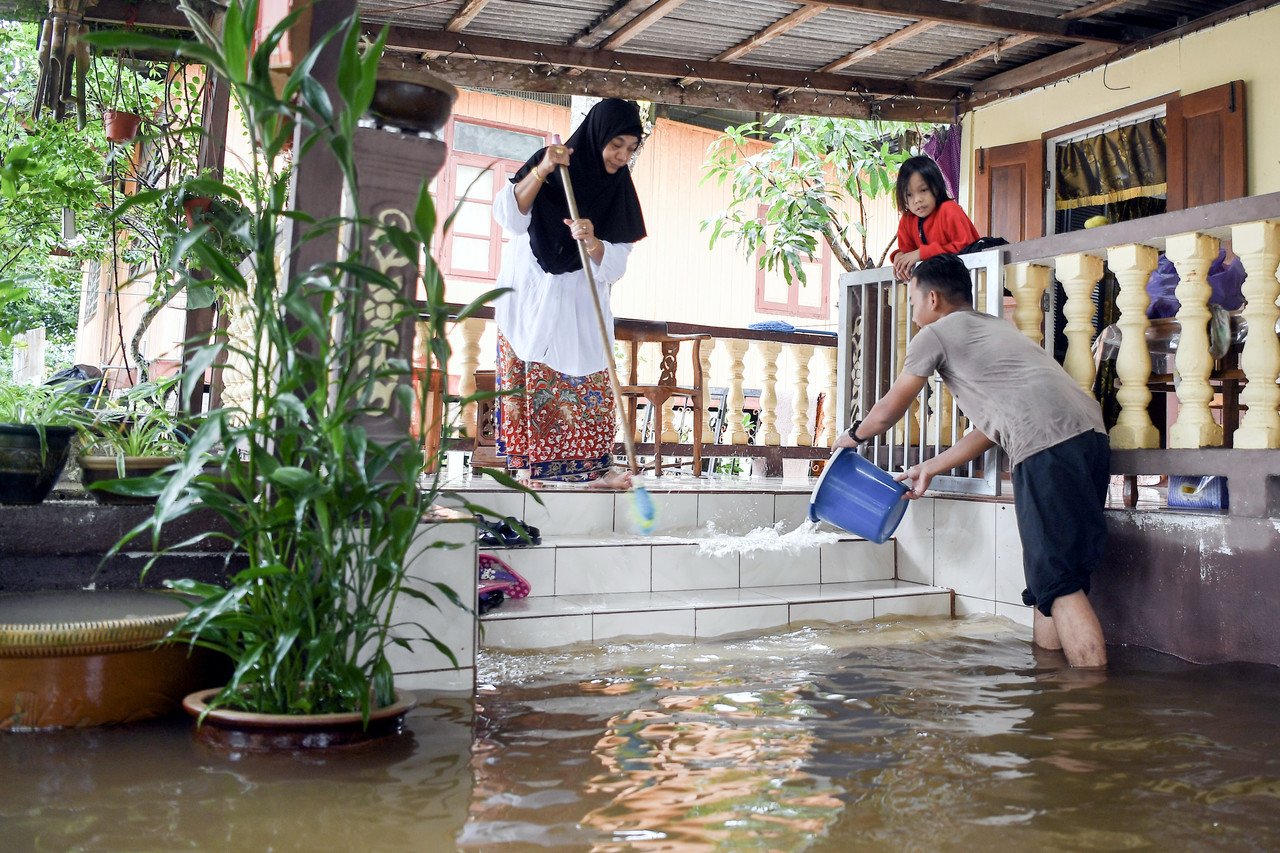  Muhammad Asrul Nasrullah Sudin, 17, (kanan) bersama ibunya Hawa Mat Amin, 53, membersih rumah selepas dilanda banjir ekoran hujan lebat di Kampung Raja hari ini. u00e2u20acu201d Foto Bernama
