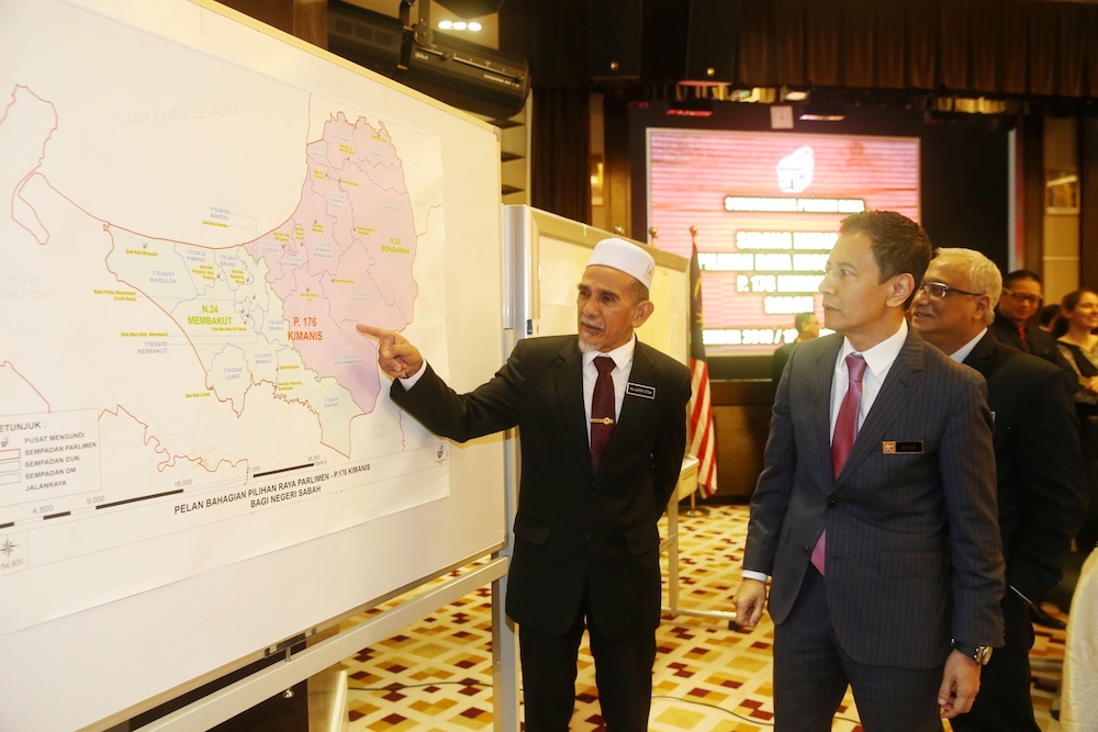 District officer Jupry Etok, also known as Jupari, talks to Election Commission chairman Datuk Azhar Azizan Harun after a press conference on the Kimanis parliamentary by-election in Putrajaya December 16, 2019. u00e2u20acu201d Picture by Choo Choy May