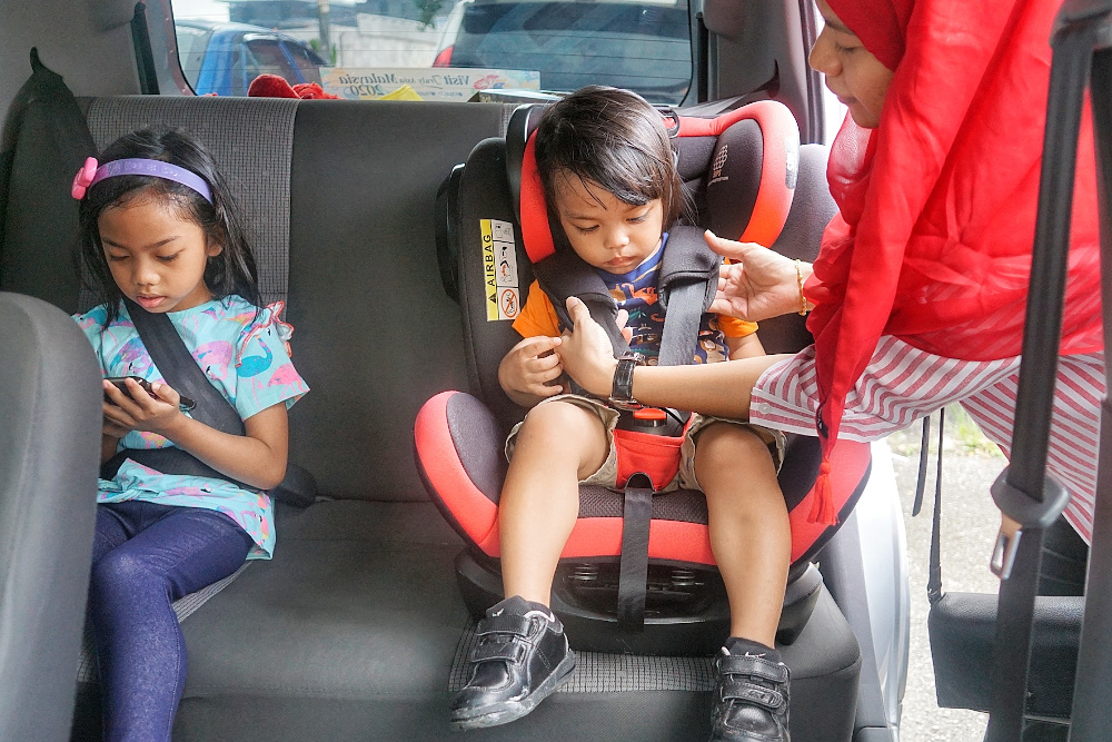A mother fastens the seat belt of her child in a car seat. u00e2u20acu201d Picture by Ahmad Zamzahuri