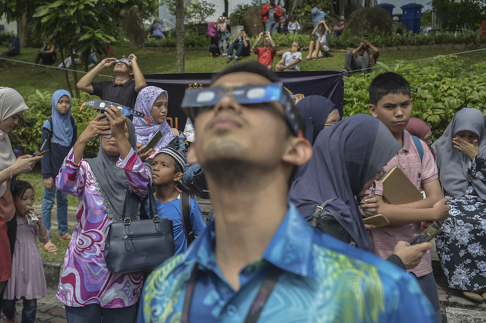 People use solar filter glasses to view the annular solar eclipse at the National Planetarium in Kuala Lumpur December 26, 2019. u00e2u20acu201d Picture by Shafwan Zaidon
