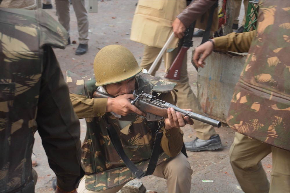 A police personnel aims his gun towards protesters during demonstrations against India's new citizenship law in Meerut on December 20, 2019. u00e2u20acu201d AFP pic