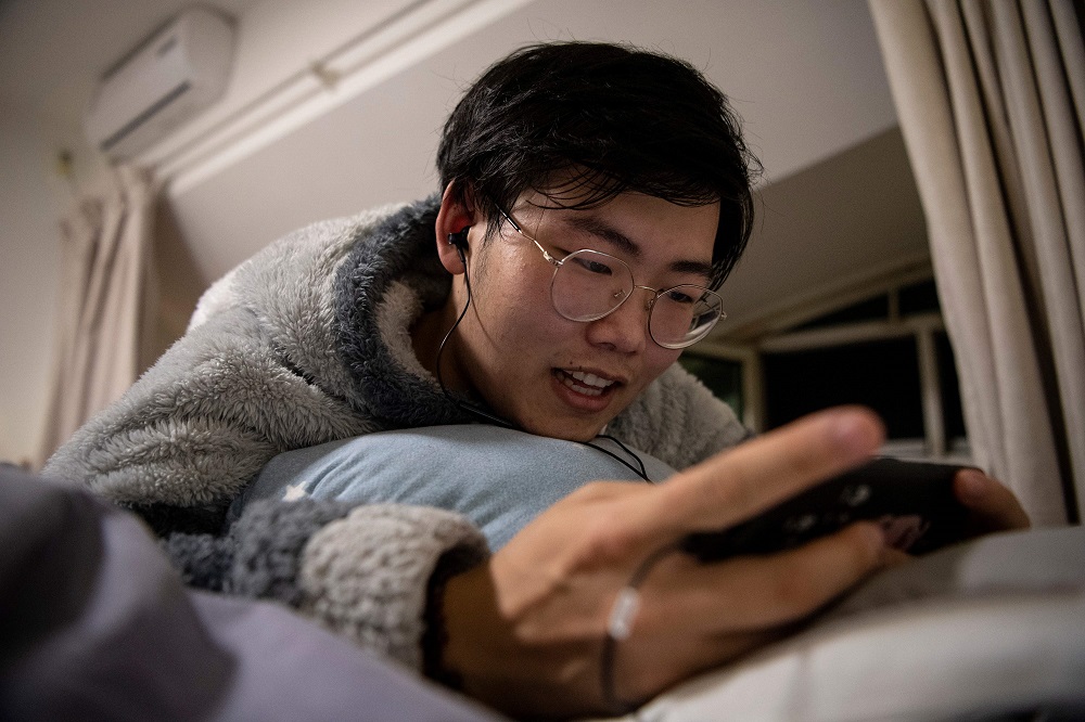 This photo taken on November 12, 2019 shows u00e2u20acu02dcvirtual boyfriendu00e2u20acu2122 Zhuansun Xu, 22, talking to a girlfriend on his phone while playing a mobile game in his room in Beijing. u00e2u20acu201d AFP pic