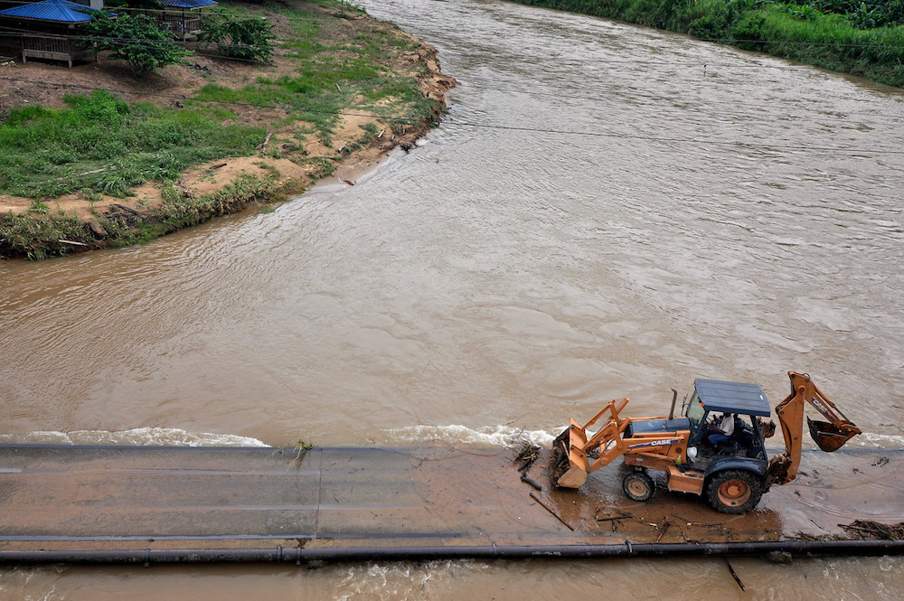 A man uses a bulldozer to clear debris from the Tamparuli suspension bridge in Tamparuli December 11, 2019. u00e2u20acu201d Bernama pic