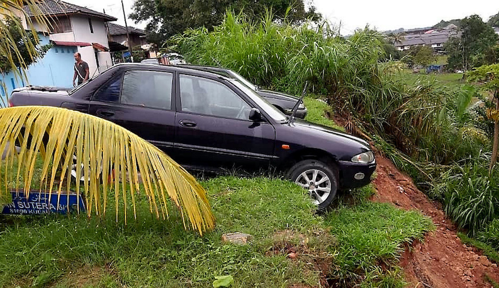 Two cars teeter on the edge of a landslide at Taman Sentosa in Kulai December 15, 2019. u00e2u20acu201d Bernama pic