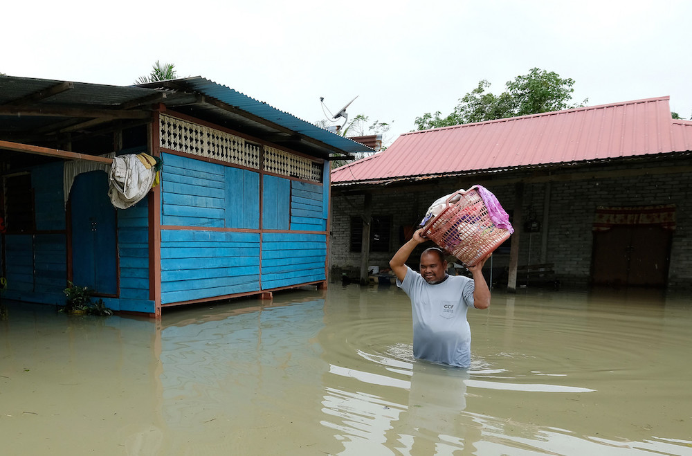 A man wades through floodwater after retrieving items from his house in Rompin December 16, 2019. u00e2u20acu201d Bernama pic