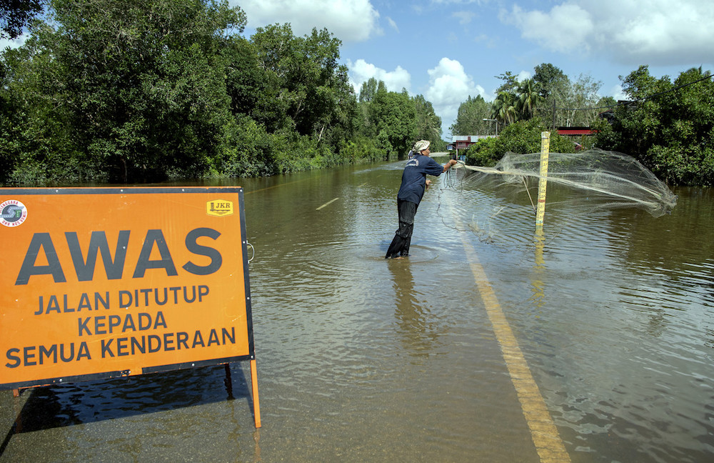 A man casts a net along a flooded Jalan Padang Licin-Gual Periok Rantau Panjang in Pasir Mas December 21, 2019. u00e2u20acu201d Bernama pic