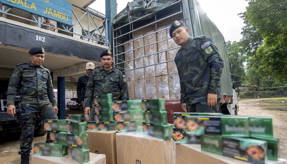 GOF 9th Battalion Operations Officer, ASP Mohamad Azlee Ismail (centre) and his men showing seized smuggled cigarettes at a media conference in Tumpat. u00e2u20acu201d Bernama pic