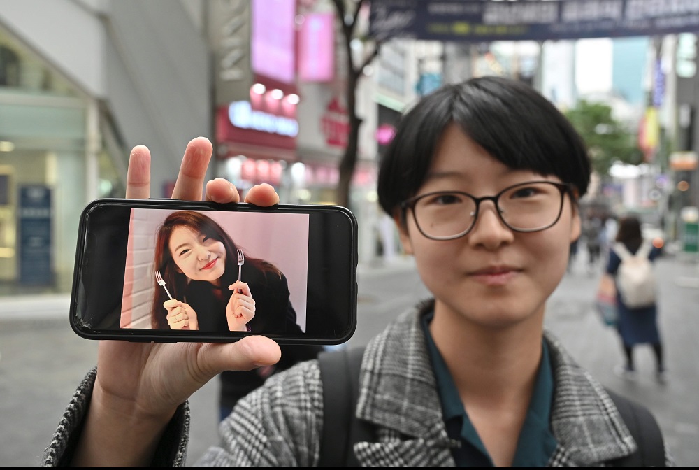 This picture taken on October 10, 2019 shows South Korean woman Yoon Ji-hye displaying an old photo of herself during an interview with AFP at the Myungdong shopping district in Seoul. u00e2u20acu201d AFP pic 