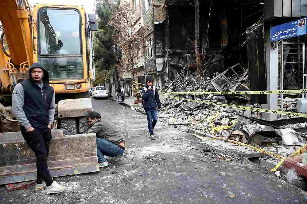People walk near a burnt bank, after protests against increased fuel prices, in Tehran, Iran November 20, 2019. u00e2u20acu201d Nazanin Tabatabaee/Wana pic via Reuters