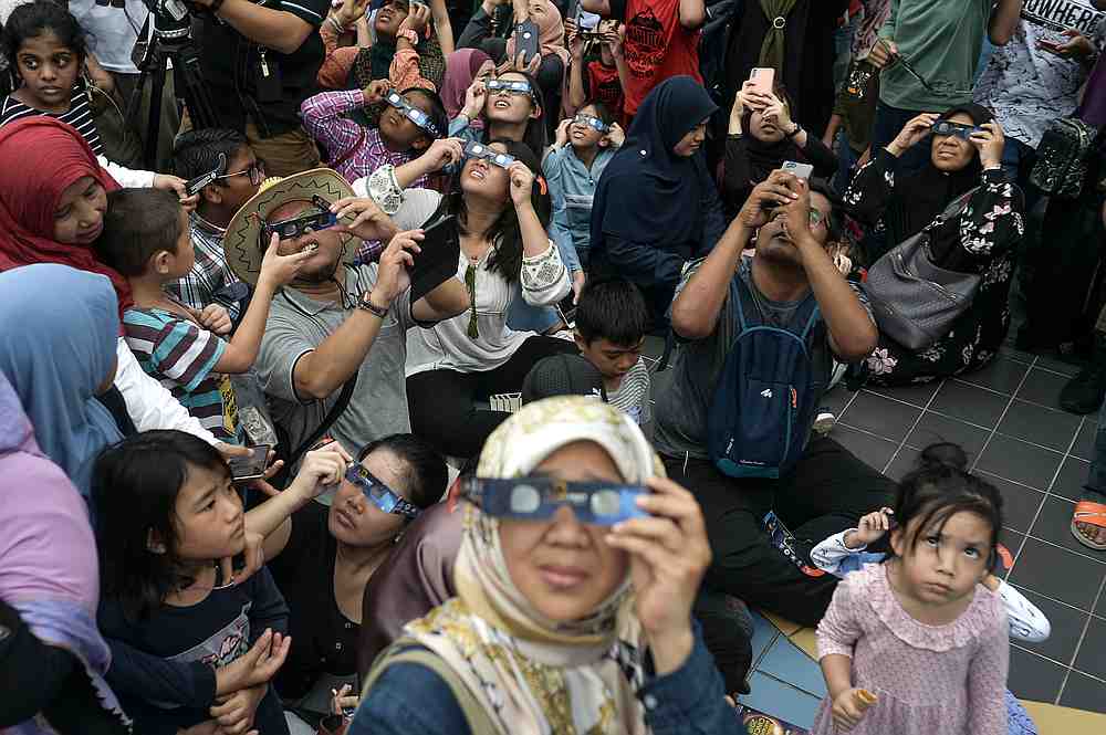 Visitors use the solar filter glasses provided by the National Planetarium to view the annular solar eclipse in the grounds of the National Planetarium in Kuala Lumpur December 26, 2019. — Picture by Shafwan Zaidon