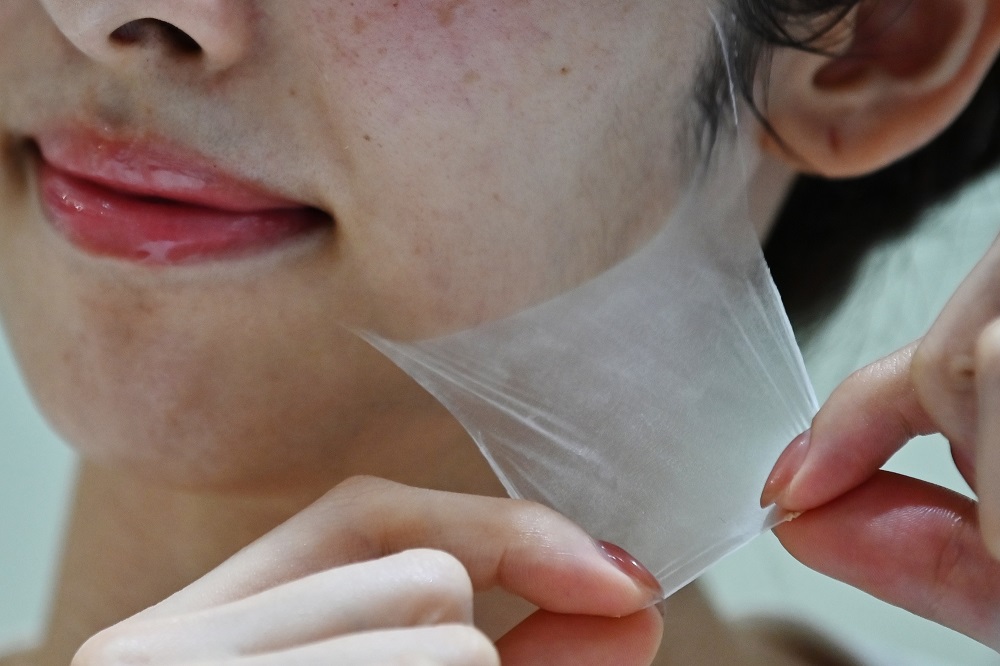 An employee for Japanese cosmetics company Kao removes a super thin transparent layer after using a palm-sized diffuser on her face, during a product demonstration in Tokyo December 4, 2019. u00e2u20acu201d AFP pic