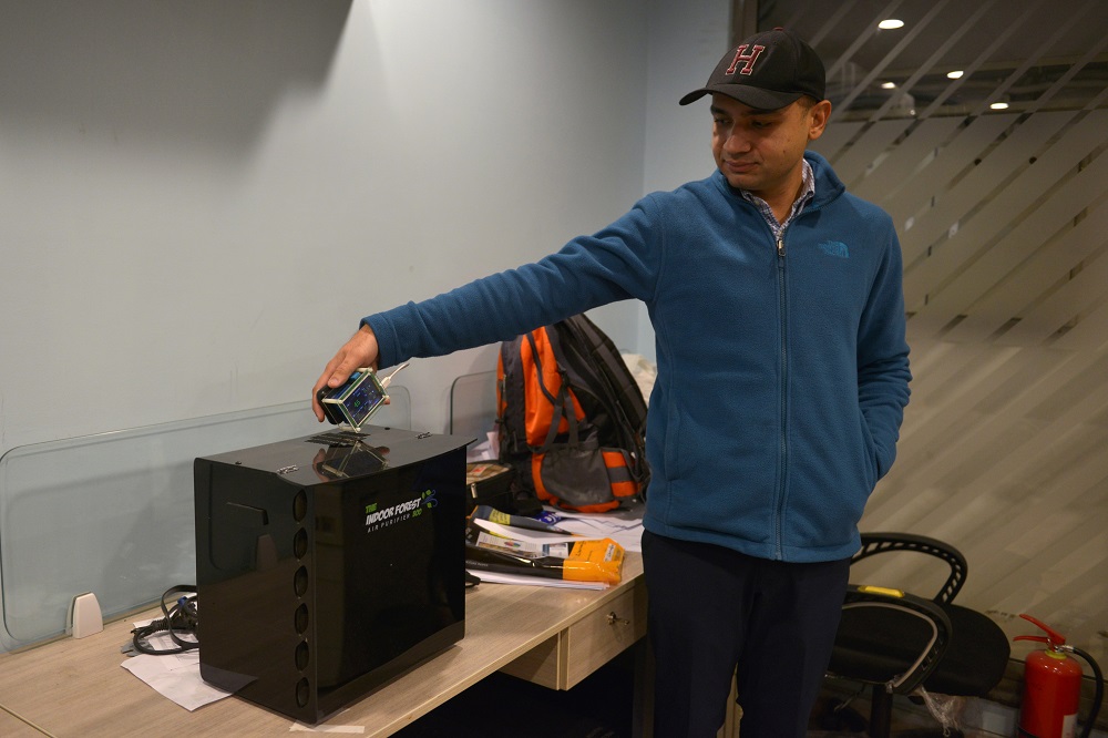 In this picture taken on December 6, 2019, inventor Hasan Zaidi checks the air quality next to his new air purifier device at the office of a customer in Lahore. — AFP pic