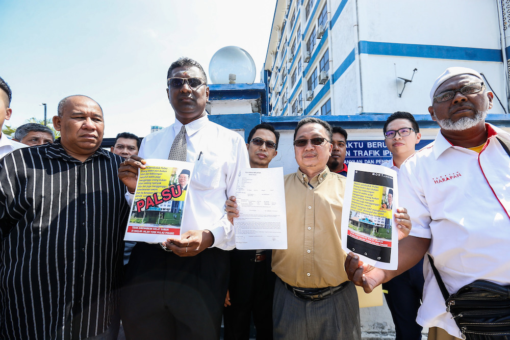 Lawyer RSN Rayer and information officer to the Penang chief minister Zahar Zainul show the police report and posters outside the Northeast District Police Station in George Town December 30, 2019. u00e2u20acu201d Picture by Sayuti Zainudin
