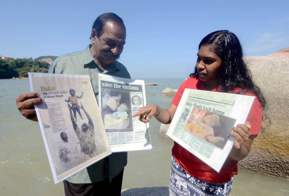 Businessman A. Suppiah (left) and daughter S. Thulasi (right) show the newspaper cuttings from 2004, when a tsunami hit Penang on Boxing Day. u00e2u20acu2022 Bernama pic