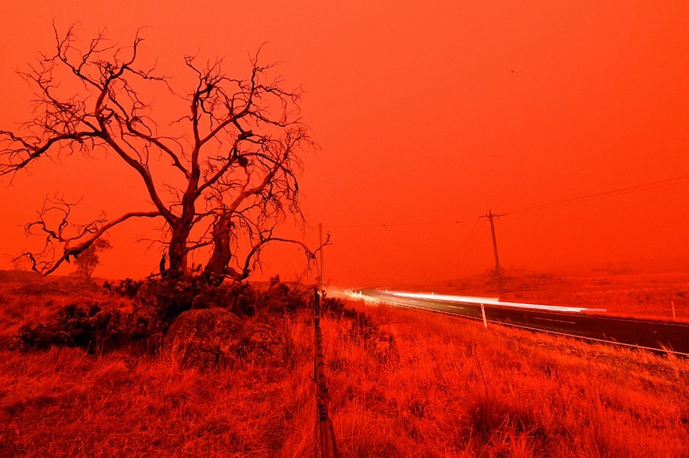 A long exposure picture shows a car commuting on a road as the sky turns red from smoke of the Snowy Valley bushfire on the outskirts of Cooma January 4, 2020. — AFP pic