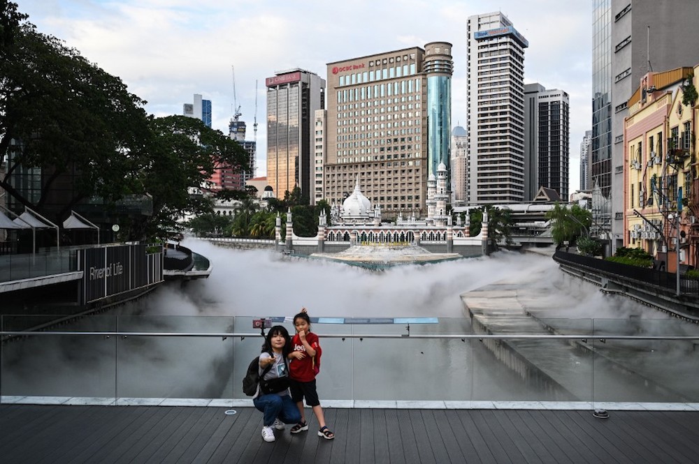 Tourists take pictures at the River of Life waterfront, covered with mist effects, where the Gombak River joins the Klang River near Masjid Jamek in Kuala Lumpur January 6, 2020. u00e2u20acu201d AFP pic