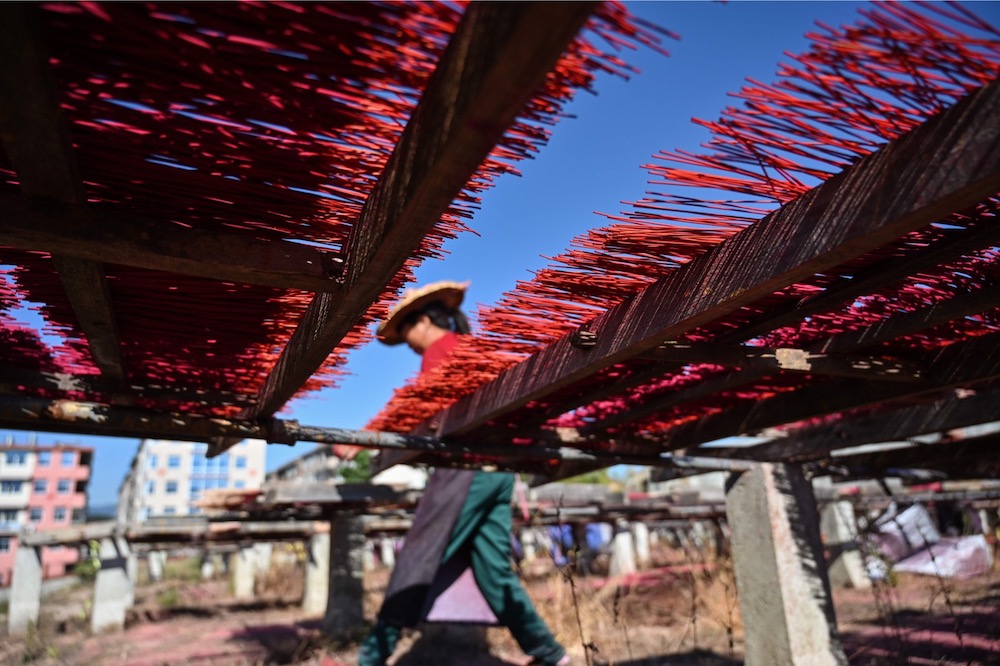 This photo taken on December 11, 2019 shows a worker placing incense sticks on wooden platforms to dry at the Fujian Xingquan Incense Factory in the city of Quanzhou in China's Fujian Province. u00e2u20acu201d AFP pic
