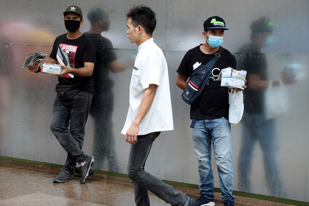 Vendors holding face masks wait for customers outside a shopping mall in Kuala Lumpur January 29, 2020. u00e2u20acu201d Reuters pic
