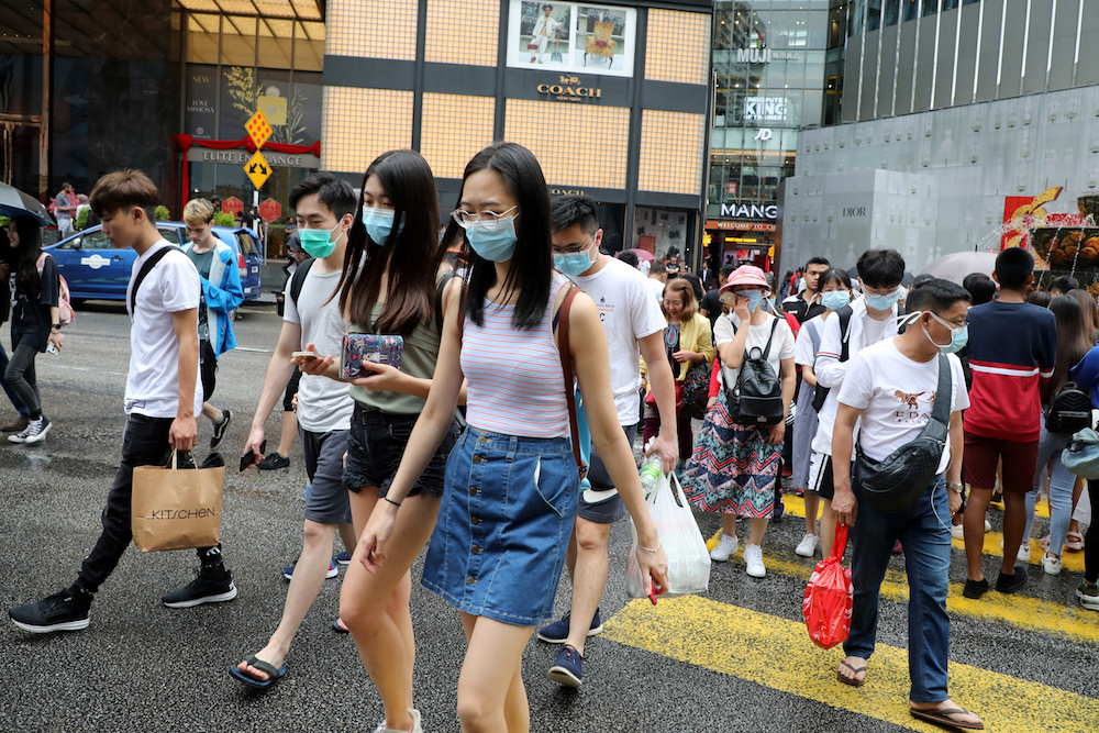 People wearing masks cross a street outside a shopping mall in Kuala Lumpur January 29, 2020. — Reuters pic