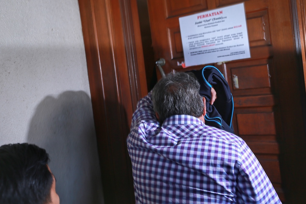 Ex-DBKL deputy director Sabudin Mohd Salleh attempts to avoid cameramen after his hearing at the KL Sessions Court January 7, 2020. u00e2u20acu201d Picture by Ahmad Zamzahuri