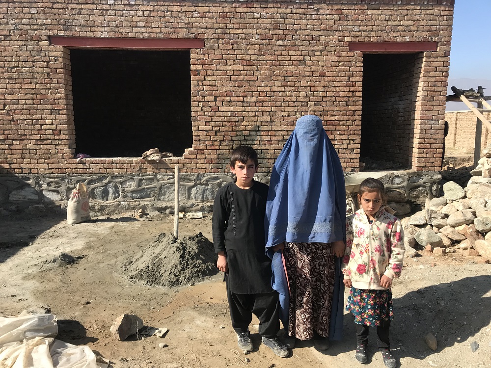 Nasim Gul stands with two of her children in front of her house that is being constructed on land allocated by the Afghan government for returning refugees and widows near Barikab, on the outskirts of Kabul November 7, 2019. u00e2u20acu201d Thomson Reuters Foundation