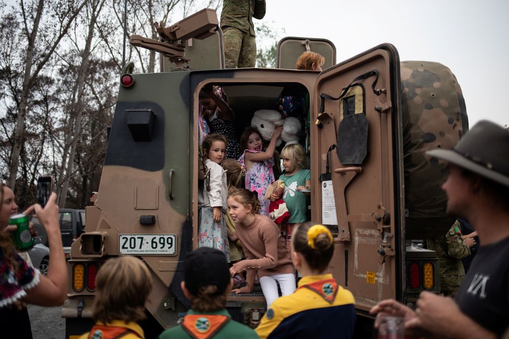 Children play inside an Australian Army forces vehicle that was expedited to help with the recovery of the town following the bushfires, 