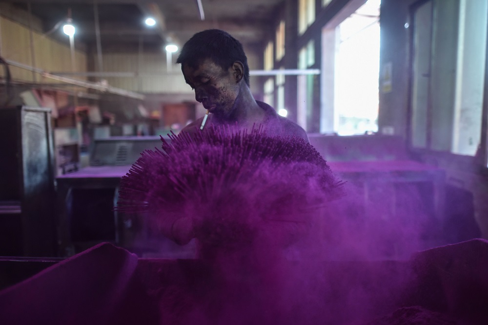 This photo taken on December 11, 2019 shows a worker covering incense sticks with coloured powder at the Fujian Xingquan Incense Factory in the city of Quanzhou in Chinau00e2u20acu2122s Fujian Province. u00e2u20acu201d AFP pic  