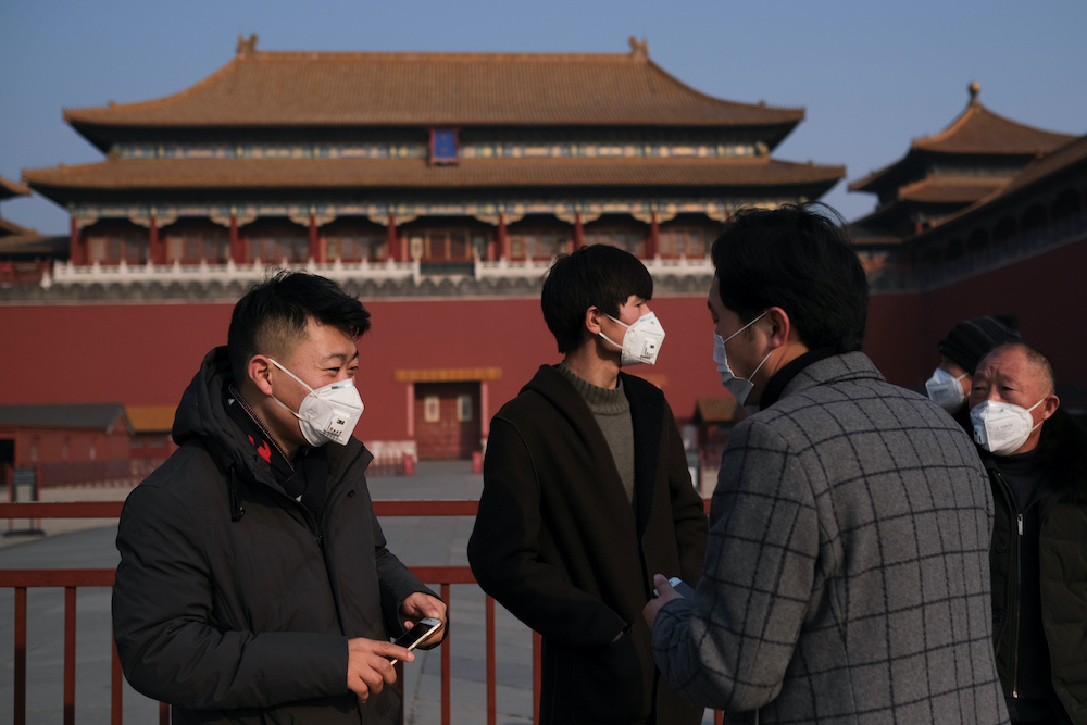 People wearing protective masks stand outside the main entrance of the Forbidden City where a notice is seen saying that the place is closed to visitors for the safety concern following the outbreak of a new coronavirus, in Beijing, China January 25, 2020