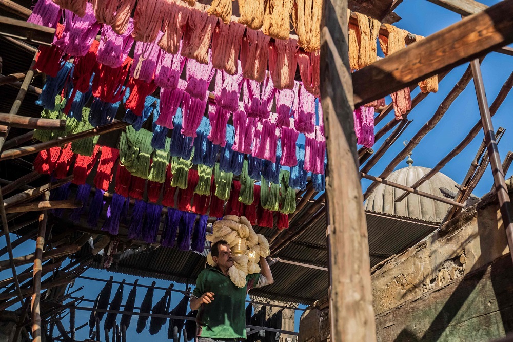 Mohamed Kamal, a 59-year-old dye worker, carries dyed yarns to hang out to dry in the sun at a traditional hand-dying workshop in the Egyptian capital Cairo’s centuries old district of Darb al-Ahmar January 21, 2020. — AFP pic