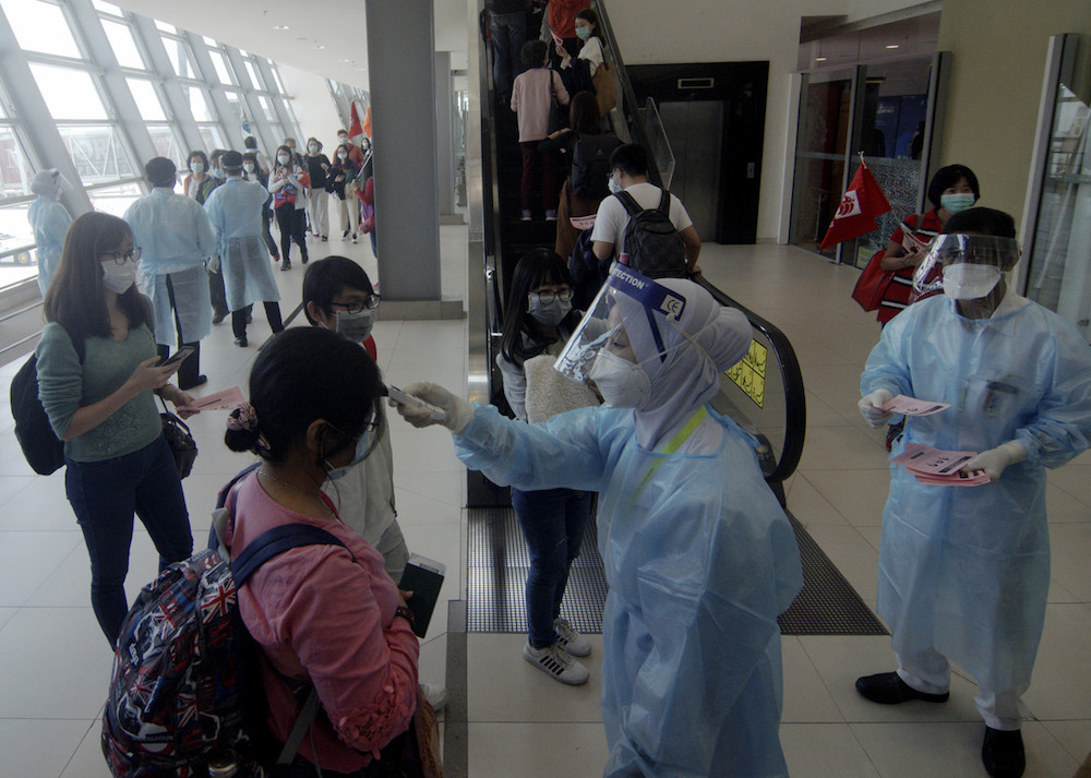 Penang Health Department workers take the temperatures of arriving travellers at Penang International Airport January 28, 2020. u00e2u20acu201d Bernama pic
